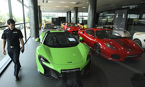 Một viên cảnh sát kiểm tra tại showroom kinh doanh siêu xe đã qua sử dụng bị nghi ngờ buôn lậu tại Thái Lan. Ảnh: Bangkok Post