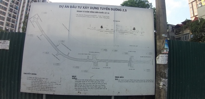 Bảng giới thiệu về dự án lấm lem bụi bẩn được dựng ở vị trí sát cạnh công trường. Chia sẻ với PV Tạp chí GTVT, chị Trương Thị Băng, một người dân sống ở khu vực gần phạm vi thi công dự án bức xúc: “Tuyến đường này đã được triển khai từ khi con tôi học lớp 1, đến nay cháu chuẩn bị thi đại học mà vẫn chưa làm xong. Đoạn từ nhà tôi ra Đầm Hồng đường rất xấu, ổ gà mọc như nấm, nắng thì bụi  bặm, mưa thì lầy lội, rác thải tràn lan khắp nơi,… ảnh hưởng rất lớn đến người tham gia giao thông và người dân sinh sống trong khu vực”.  