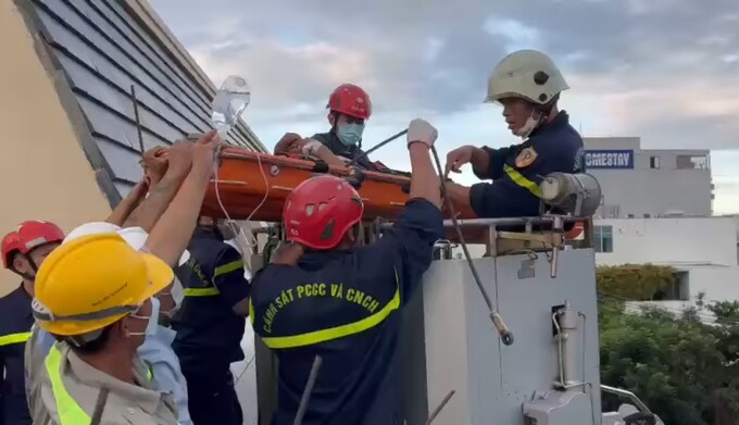 2 công nhân bị thương được lực lượng chức năng dùng xe thang đưa xuống dưới để đi cấp cứu.