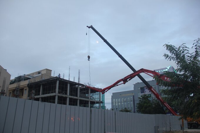 Lực lượng chức năng dùng cần cẩu kéo cần bơm bê tông đưa thi thể mắc kẹt ra ngoài. 