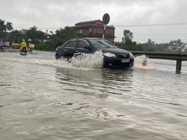 Nước lũ tràn qua quốc lộ 1 ở Quảng Nam, phương tiện qua lại khó khăn - Ảnh 1.