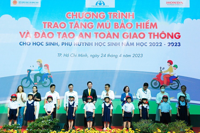 Các đại biểu trao tặng mũ bảo hiểm cho các em học sinh lớp Một và lớp Hai trường Tiểu học Lạc Long Quân, TP.HCM.
